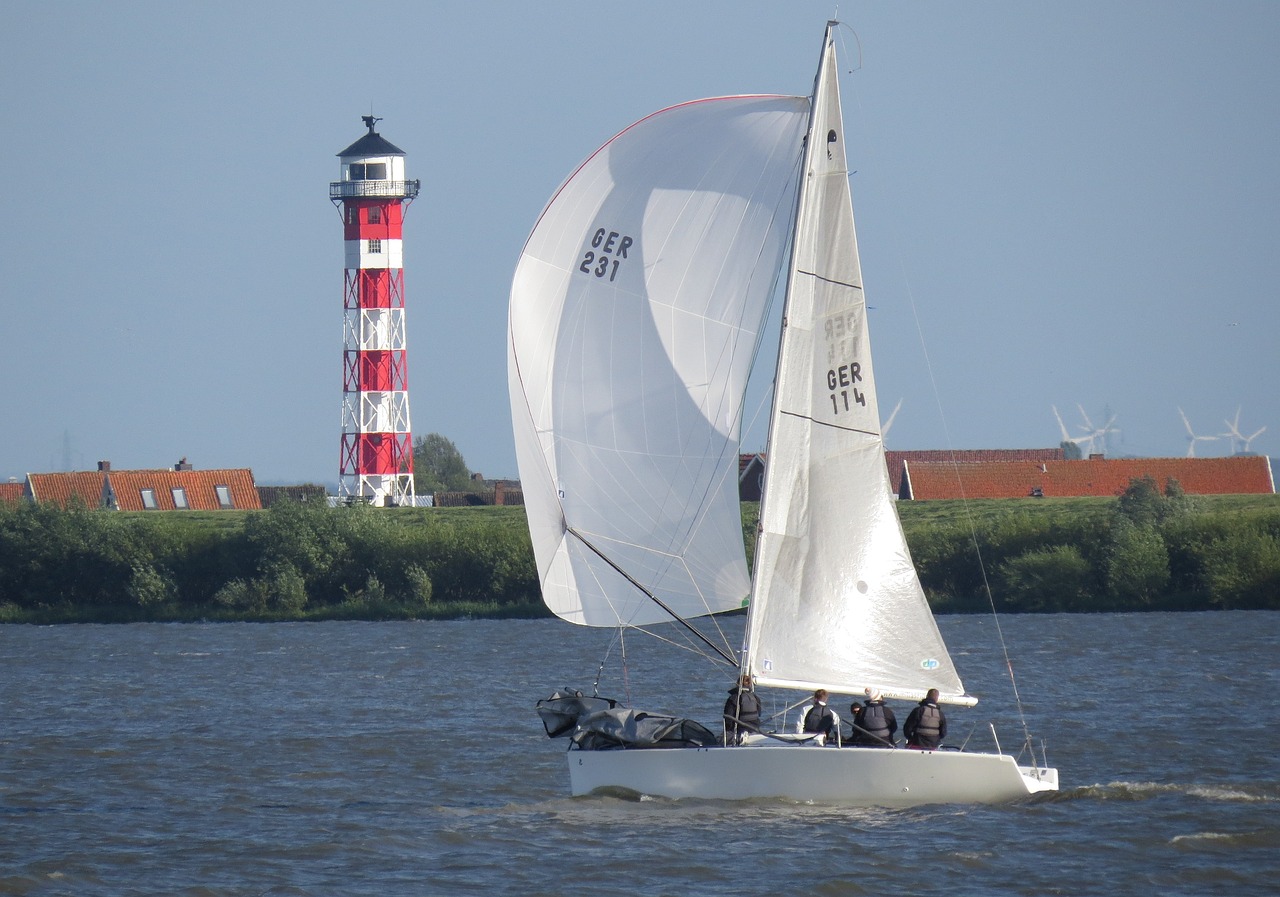 Segelboot auf der Elbe mit Leuchtturm im Hintergrund